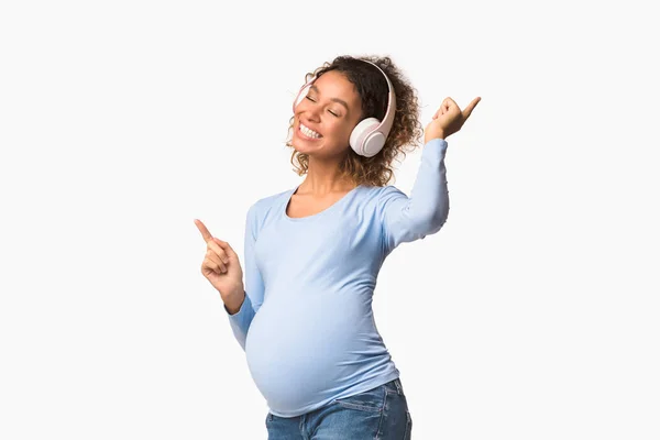 Mujer embarazada afro alegre escuchando música y bailando —  Fotos de Stock