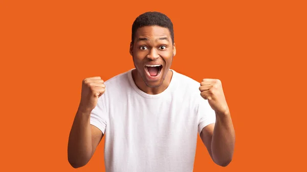Afro man shouting over orange studio background — ストック写真