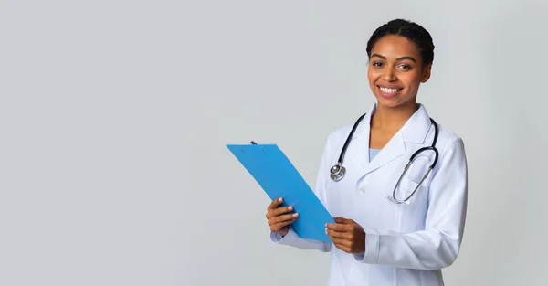 Retrato de jovem preto feminino médico estagiário segurando prancheta azul — Fotografia de Stock