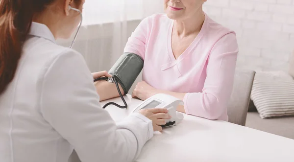 Médico com tonômetro medindo a pressão arterial do paciente sênior — Fotografia de Stock