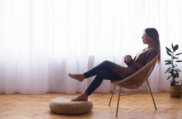 Mulher pacífica desfrutando de café quente perto da janela em casa — Fotografia de Stock