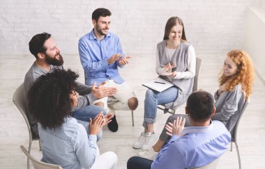 Arkadaş canlısı terapi grubu üyeleri, rehabilitasyondaki genç kadınları alkışlıyor.