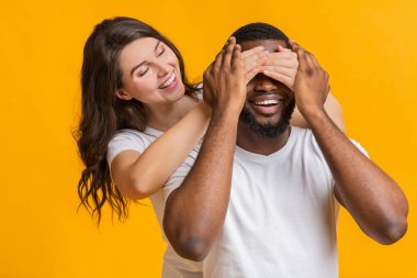 Loving girlfriend surprising her boyfriend, covering his eyes from behind clipart