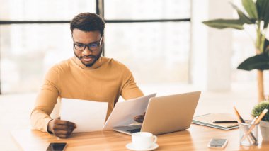 Afro yöneticisi modern ofiste raporları kontrol ediyor
