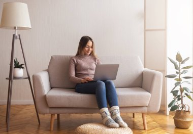 Evde dizüstü bilgisayarda örülü çoraplarla sörf yapan tatlı bir kız.