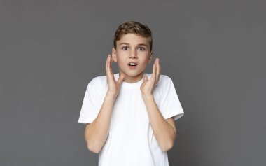 Amazed teen boy looking at camera with distrustful expression clipart