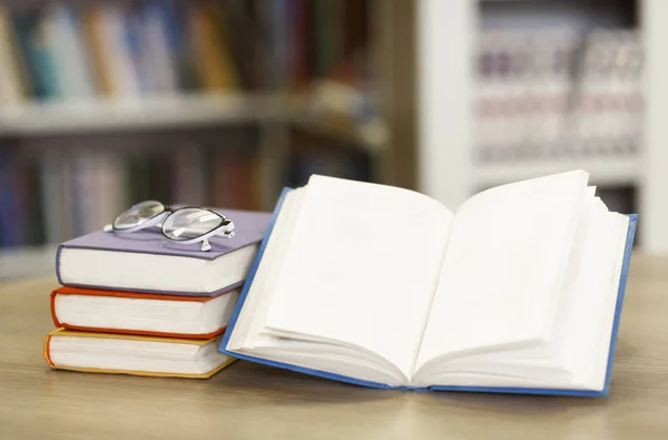 Geopend boek close-up met boekenplank achterin — Stockfoto