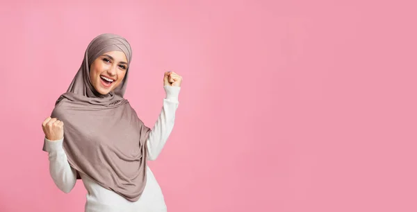 Muszlim lány fejkendőben ünnepli a sikert, felemeli a kezét és kezet rázott. — Stock Fotó