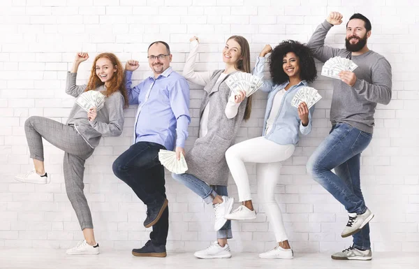 Glückliche Menschen, die sich über Erfolg freuen und mit viel Dollargeld posieren — Stockfoto