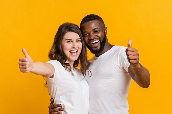 Happy Interracial Couple Hugging And Showing Thumbs Up At Camera