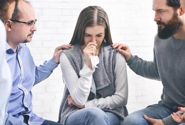 Miembros del grupo que apoyan a una mujer maltratada víctima de violencia doméstica en sesión de terapia — Foto de Stock