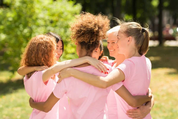 Donne in t-shirt rosa che si abbracciano durante la riunione del gruppo di supporto all'aperto — Foto Stock