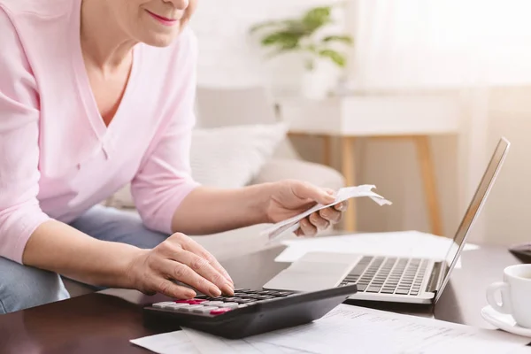 Seniorin zählt Rechnungen mit Taschenrechner zu Hause — Stockfoto