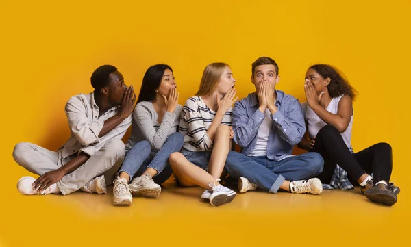 Grupo de estudiantes chismorreando sobre fondo amarillo —  Fotos de Stock