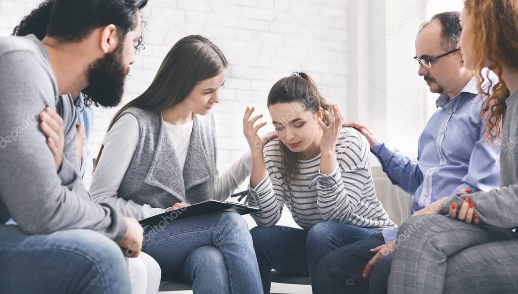 Depressed woman sharing her problems with group on therapy session