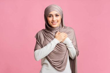 Elleri göğsünde başörtüsü olan minnettar Arap kadın şükranlarını sunuyor.