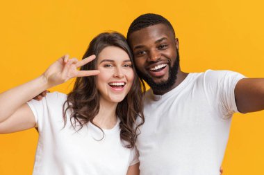 Mutlu iki uluslararası arkadaş selfie çekip barış işareti gösteriyorlar.