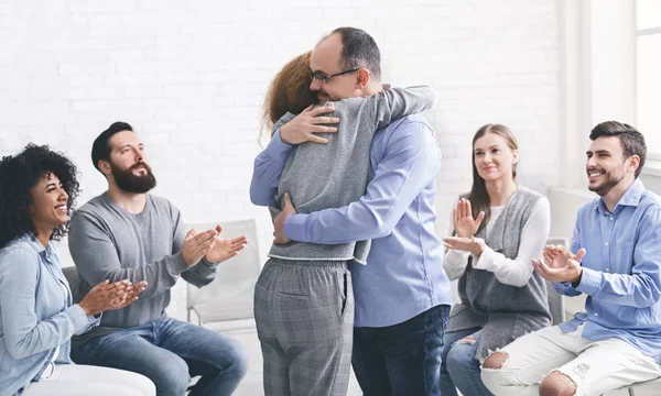 Positive people hugging during group therapy session in rehab