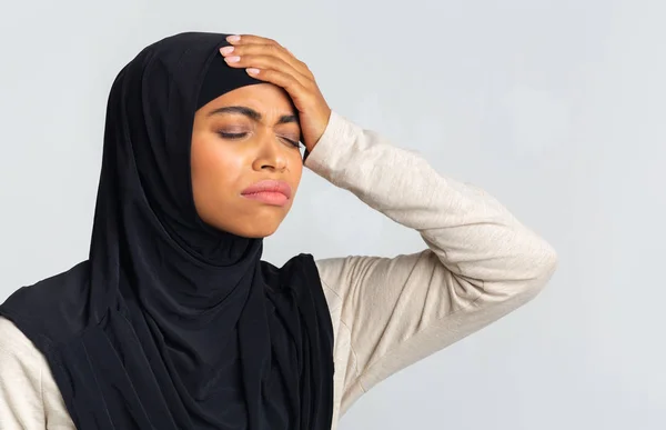 Svart islamsk kvinne i Hijab som tar på pannen sin, lider av hodepine – stockfoto