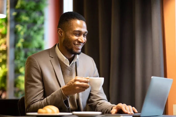 Afro manager drinking tea and using pc