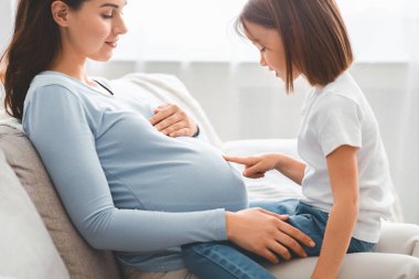 Küçük çocuk hamile, koca göbekli anneyi izliyor.