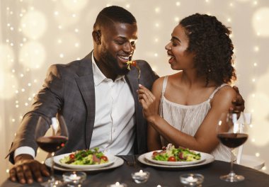 Genç çift lokantada vakit geçirirken birbirlerini besliyorlar.