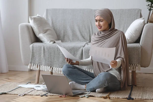 Несчастная арабская женщина, сидящая на полу с документами и ноутбуком — стоковое фото