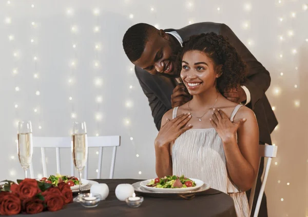 Amorös svart man i kostym ger kvinna elegant halsband — Stockfoto