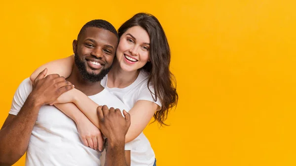 Retrato de feliz pareja multirracial abrazando, posando juntos sobre fondo amarillo — Foto de Stock