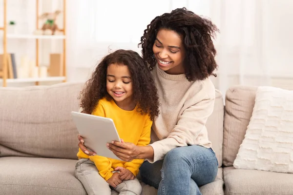 Moeder en dochter met behulp van tablet kijken cartoons zitten op de bank — Stockfoto