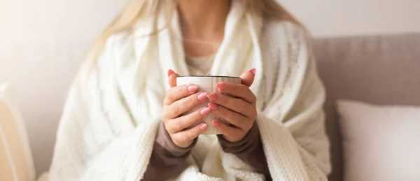 Jovem mulher aquecendo as mãos com xícara de café quente — Fotografia de Stock