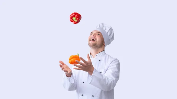 Spannende chef-kok Jongleren Sweet Peppers Staande in Studio, Panorama — Stockfoto