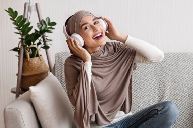 Başörtüsü ve kablosuz kulaklık takan mutlu Müslüman kız portresi