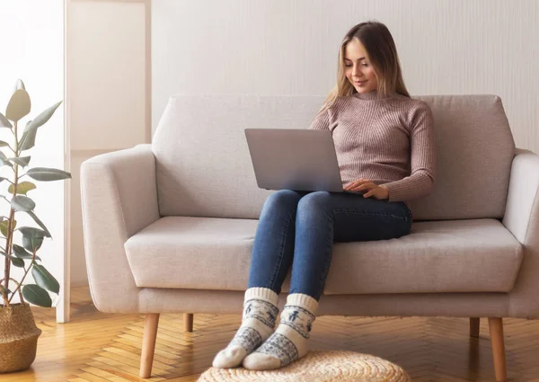 Молода дівчина вчиться з ноутбуком вдома, сидячи на дивані — стокове фото