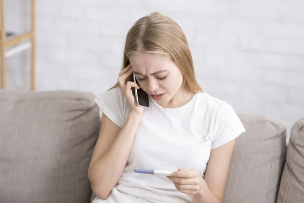 Aggódó nő beszél telefonon, terhességi tesztet tart. — Stock Fotó