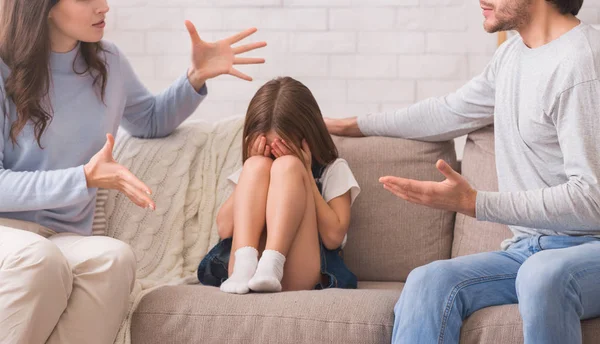 Onschuldig klein meisje zit tussen ruziën ouders en huilen — Stockfoto