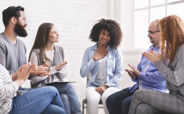 Rehabilitasyon grubundaki insanların desteğini takdir eden mutlu bir afro kadın.