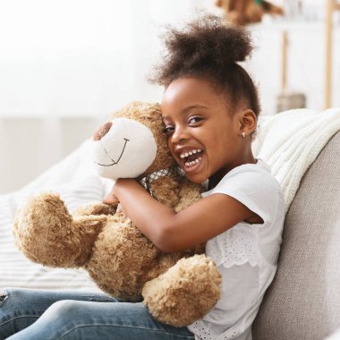 Büyük oyuncak ayıyla neşeli afro kız portresi