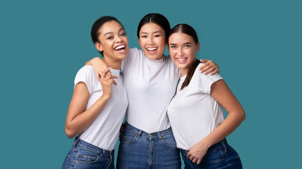 Tres chicas felices y diversas abrazándose en el fondo del estudio de turquesa, Panorama — Foto de Stock