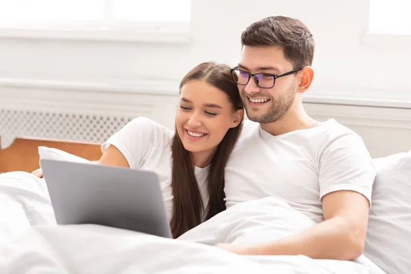 Laptop-ot használó házastársak otthon ülnek az ágyban — Stock Fotó