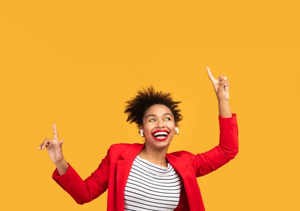 Sorrindo afro mulher ouvindo música aponta para cima — Fotografia de Stock