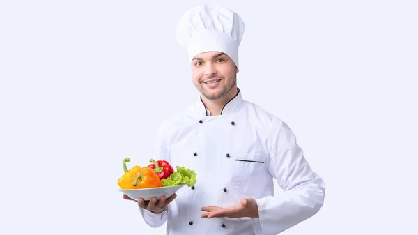 Küchenchef hält Teller mit Gemüse im Stehen, Studioaufnahme, Panorama — Stockfoto