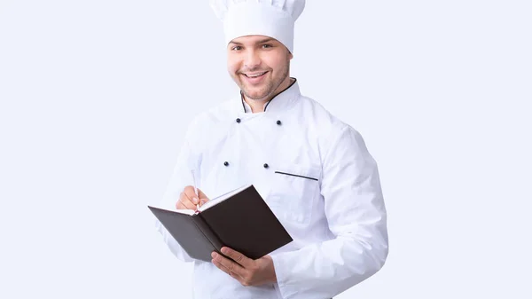 Chef écrivant des recettes dans un livre culinaire sur fond blanc, Panorama — Photo