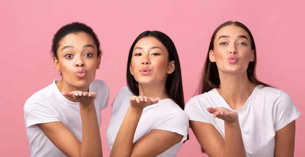 Tres Millennial niñas enviando aire beso posando sobre rosa fondo —  Fotos de Stock