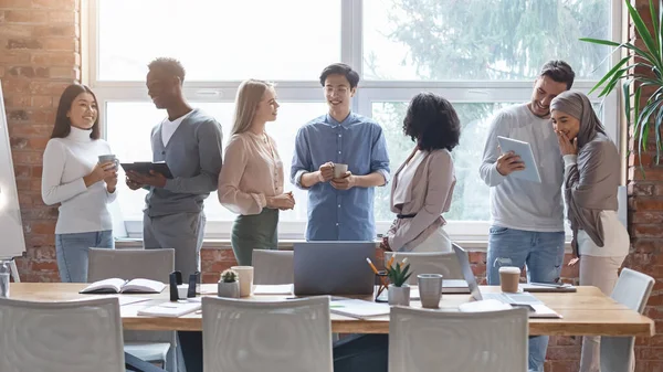 Group of multiracial young people talking while coffe break