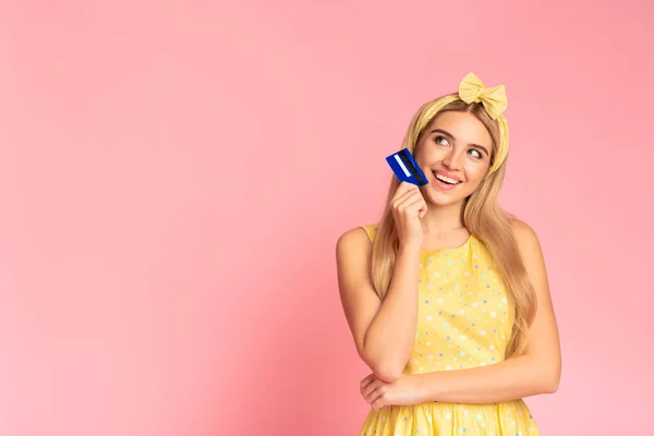 Soñando chica sosteniendo tarjeta de crédito pensando en el mercado — Foto de Stock