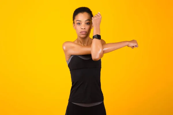 Donna che esercita stretching Deltoid braccio muscolare in posa su sfondo giallo — Foto Stock