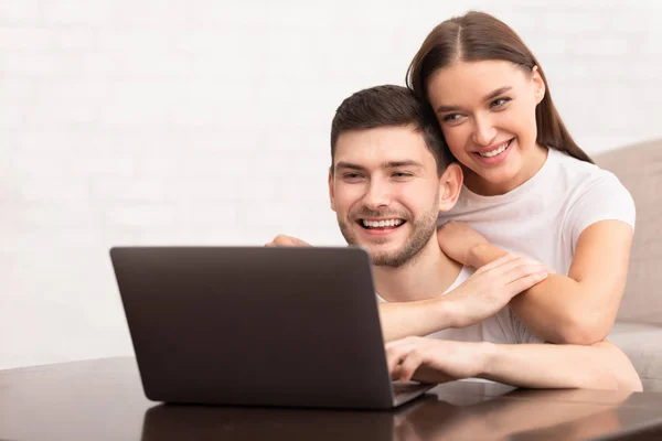 Cara trabalhando no laptop sentado com namorada no sofá interior — Fotografia de Stock