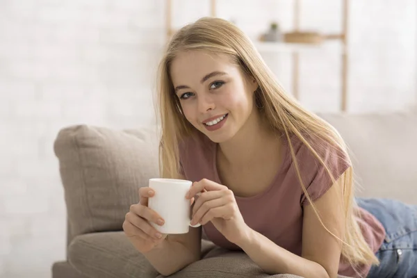 Portret van jonge blonde vrouw die thuis koffie drinkt — Stockfoto