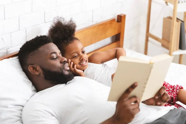 Amoroso pai africano lendo contos de fadas para sua pequena filha — Fotografia de Stock